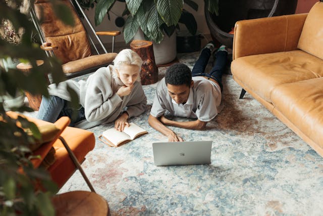 Man and woman sat on the floor in front of laptop.