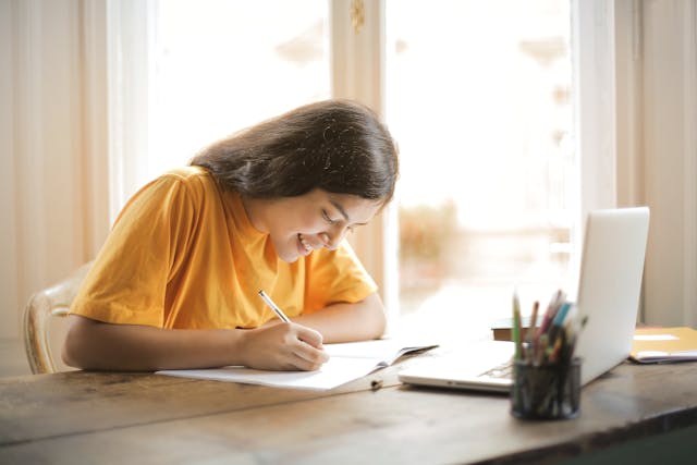 Woman in Yellow Shirt Writing on White Paper
in her partner's native language